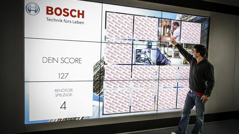 Mann spielt Memory Touch Game von Bosch auf einem großen Bildschirm