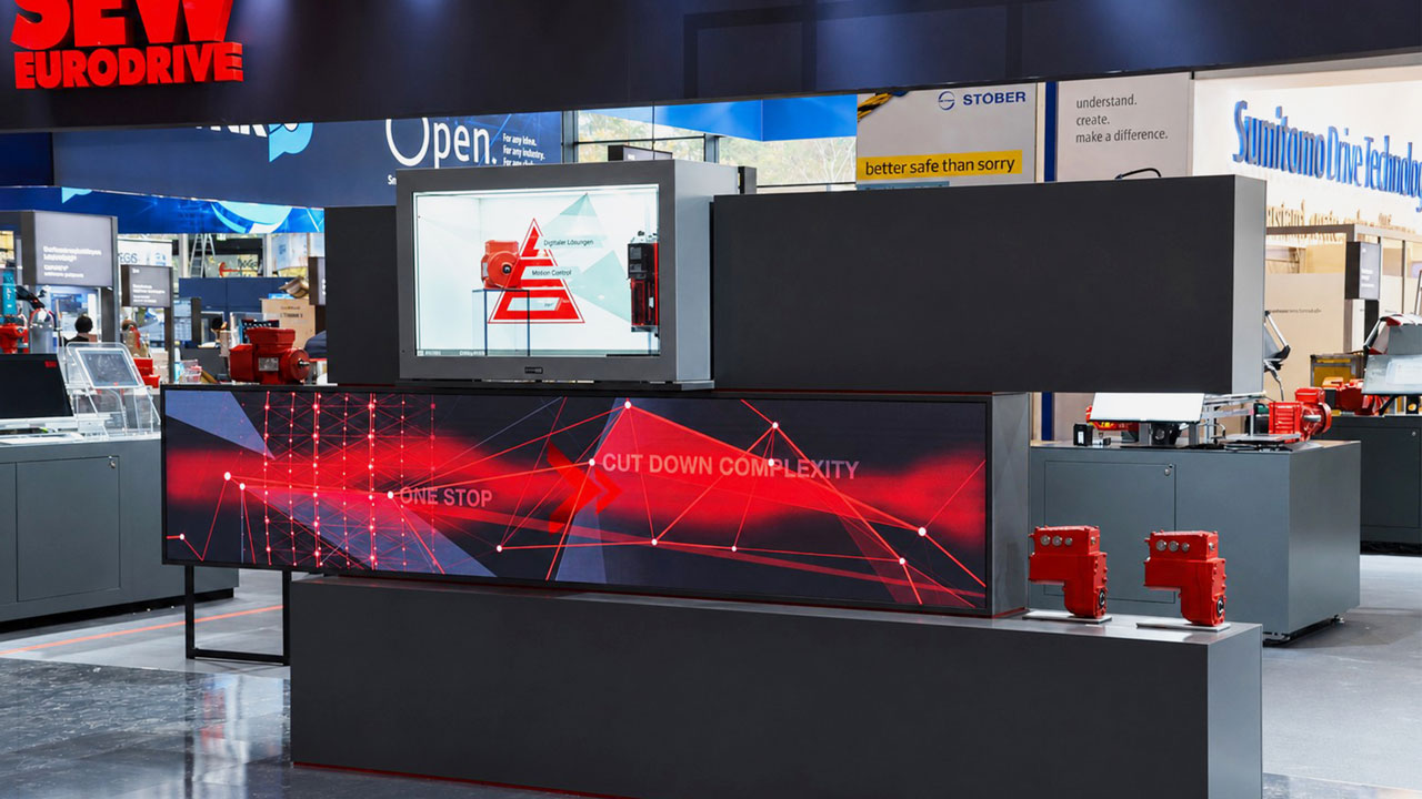 commacorss 2026 hybride messekonzepte 4 1 Messestand-Eyecatcher von Stäubli mit Mitarbeiter der Besucher eine Anwendung demonstriert